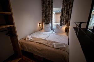 una piccola camera da letto con un letto e asciugamani di Das Posthaus - Amt a Greetsiel