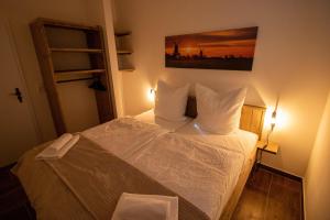 una piccola camera da letto con un letto con lenzuola bianche di Das Posthaus - Amt a Greetsiel