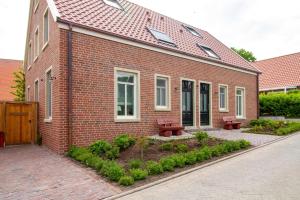 a brick building with two benches in front of it at Up Besöök - Rapsblüte mit Infrarotsauna in Krummhörn