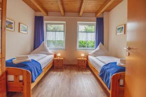 duas camas num quarto com duas janelas em Haus Merlin - Silbermöwe em Greetsiel