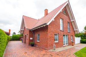 uma casa de tijolos vermelhos com um telhado vermelho em Haus Merlin - Silbermöwe em Greetsiel