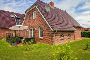 a red brick house with an umbrella in the yard at Huus Viskert in Krummhörn