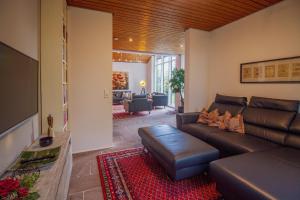 a living room with a leather couch and a television at Architektenhaus am Pewsumer Tief in Krummhörn