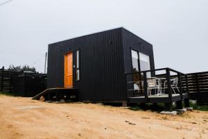 a black tiny house on a dirt road at Cabaña Dos personas en Punta de Lobos PUERTO LA MAR in Pichilemu