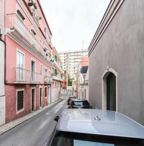 un coche aparcado en una calle de la ciudad con edificios en Vita Portucale ! Campo Ourique Design w/ Balcony, en Lisboa