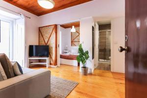 Una sala de estar con un sofá y un televisor. en Vita Portucale ! Campo Ourique Design w/ Balcony, en Lisboa