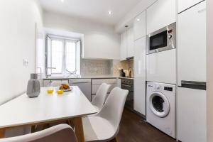 Una cocina blanca con una mesa y sillas blancas. en Vita Portucale ! Campo Ourique Design w/ Balcony, en Lisboa