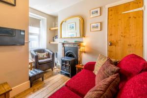 un soggiorno con un divano rosso e un camino di Birds Nest Cottage Looe a Looe