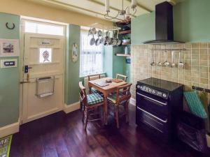 una cucina con tavolo e una cucina con pareti verdi di Birds Nest Cottage Looe a Looe