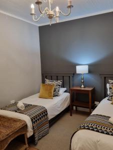a bedroom with two beds and a chandelier at Silo Cottage in Underberg