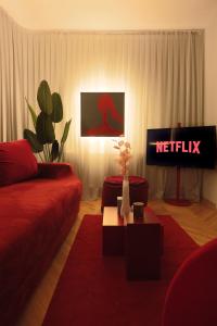 a living room with a red couch and a television at Etern Stays - Maroon Apartment in Pristina +11 photos
