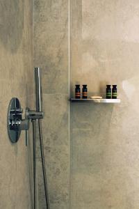 a shower with a glass door with bottles on a shelf at Calistus Mykonos in Mikonos +23 photos