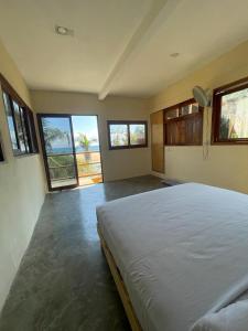 1 dormitorio con 1 cama grande en una habitación con ventanas en La Playa Hostel, en Mazunte