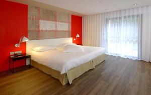 - une chambre avec un grand lit et un mur rouge dans l'établissement Logis Domaine du Moulin Cavier, à Avrillé