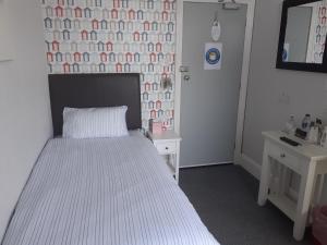 a bedroom with a white bed and two tables at South Beach B & B in Lowestoft
