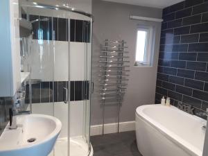 La salle de bains est pourvue d'une douche, d'une baignoire et d'un lavabo. dans l'établissement South Beach B & B, à Lowestoft