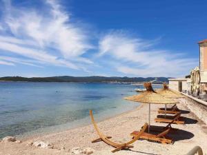 een strand met stoelen en een parasol en het water bij Apartman Mela in Orebić