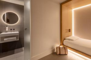 a small bathroom with a bed and a mirror at Zedwell Piccadilly Circus in London
