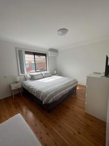 a bedroom with a large bed and a window at The Entrance & Shelly Beach Holiday House in Long Jetty