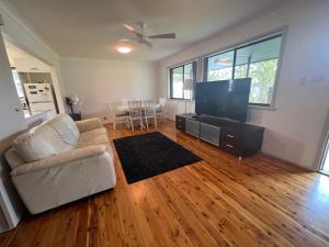 a living room with a couch and a flat screen tv at The Entrance & Shelly Beach Holiday House in Long Jetty