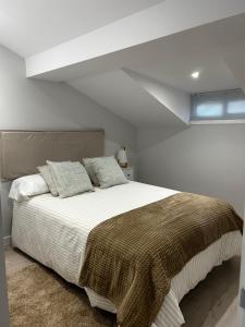 1 dormitorio blanco con 1 cama grande con manta marrón en PISO CENTRO - CONCORDIA, en Ourense
