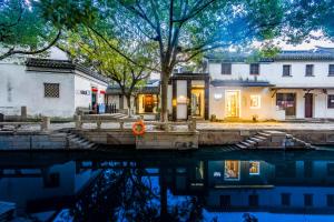 a house with a pool of water in front of it at Tongli 1917 Best South Inn in Suzhou