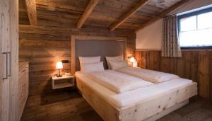 a bedroom with a bed in a wooden room at Alpin Lodges - Moderne Appartements mit Zugang zu 3000 qm SPA Panoramahotel Oberjoch in Bad Hindelang