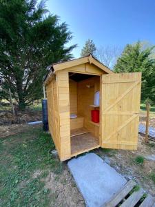 a wooden shed with a door in the grass at Gîte pèlerin - "Les Sources" - Chambres Dortoirs in Le Vigan