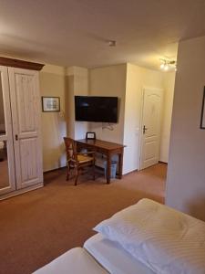 - une chambre avec un bureau, une télévision et un lit dans l'établissement Inselhotel Kapitän Tadsen / Amrum, à Nebel