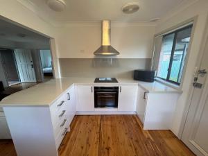 a kitchen with white cabinets and a stove top oven at The Entrance & Shelly Beach Holiday House in Long Jetty +6 photos