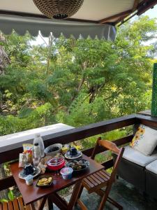 a table with food on a balcony with a view of trees at Apartamento Praia do Forte in Mata de Sao Joao