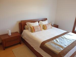 um quarto com uma cama com almofadas e uma mesa de cabeceira em Welcome Here Parque Lumiar 1 em Lisboa