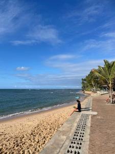 a person sitting on a bench on the beach at Apartamento Praia do Forte in Mata de Sao Joao +27 photos