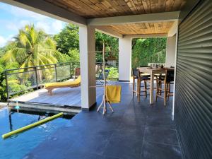 a patio with a table and a swimming pool at Le CAILLOU in La Trinité