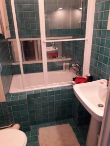 a green tiled bathroom with a toilet and a sink at Stella maris in Carnac