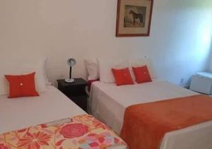 een kamer met 2 bedden en rode kussens bij Pousada Del Mare di Ponta Negra in Maricá