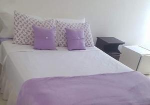 een slaapkamer met een groot bed met paarse kussens bij Pousada Del Mare di Ponta Negra in Maricá