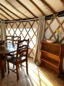 ein Esszimmer mit einem Tisch, Stühlen und einem Fenster in der Unterkunft Redwood - the BIG yurt in Fernhurst
