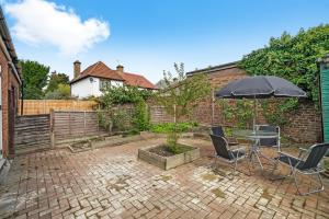 a patio with a table and chairs and an umbrella at Boutique Heathrow Studio's - Parking - Garden in Harmondsworth