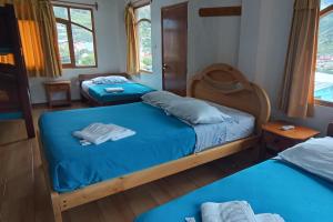 two beds in a room with blue sheets at Hostal Colibri 2 in Baños