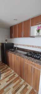 a kitchen with wooden cabinets and a stove top oven at Hermoso apartamento en conjunto cerrado cerca al aeropuerto in Bogotá