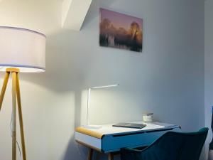 a desk with a lamp and a laptop on it at ruhig-Nespresso-Netflix-Parken-luxuriös in Wuppertal
