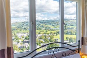 a bedroom with a view of the countryside through windows at Lakeland View Coniston in Coniston