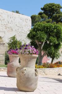 two large vases filled with flowers on a sidewalk at Hotel Boutique Il Castellino Relais in Vieste