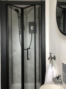 a shower with a glass door next to a sink at The Metropolitan Guest House in Whitley Bay