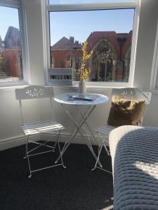 een tafel en 2 stoelen in een kamer met een raam bij The Metropolitan Guest House in Whitley Bay