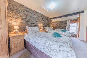 una camera da letto con un letto e un muro di pietra di Middlefield Cottage Coniston Water a Coniston