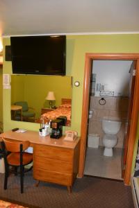 a hotel room with a desk and a bathroom at The Village Motel in Richfield Springs