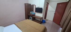 a bedroom with a bed and a desk with a television at East Coast Hotel in Kuantan