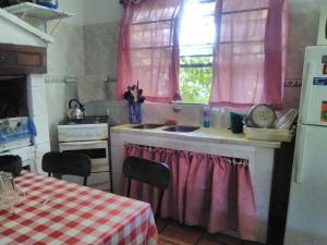 cocina con cortinas rosas, fregadero y mesa en Delastres, en Cuchilla Alta